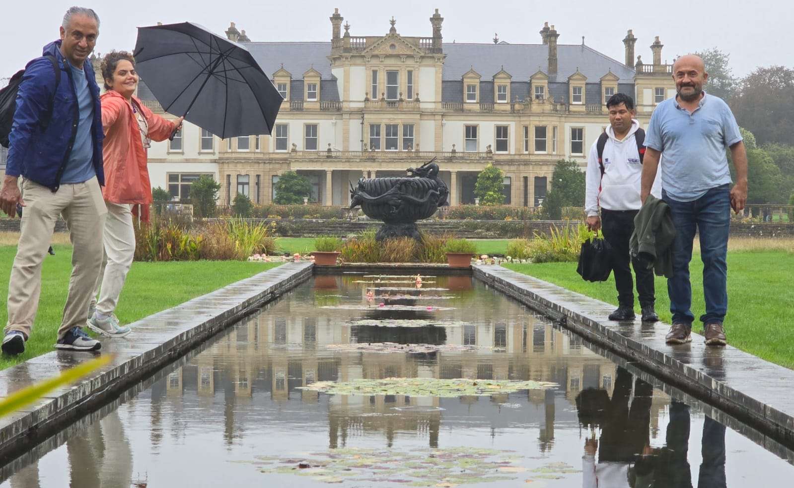 A group gathered beside a reflecting pool at a historic estate